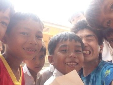 大学時代、旅先で子どもたちと笑顔で写る松本じゅんや